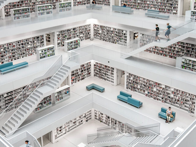 Grand escalier ouvert sur les rayonnages d'une bibliothèque entièrement blanche